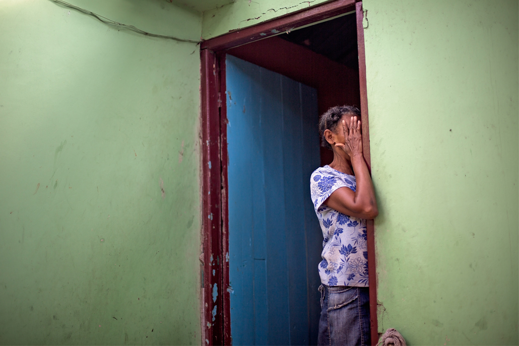 Woman covering face in red doorway and green wall